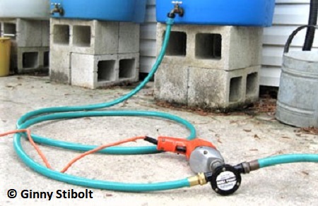 A drill pump transferred water between the old barrels and the new barrels.  
		  Using the motor of an old drill saves money. Photo by Stibolt