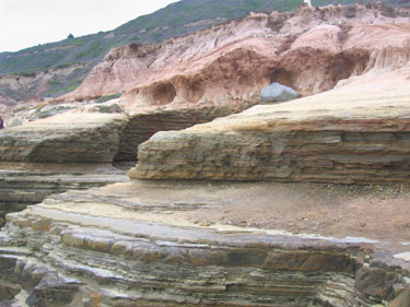 The layers of sedimentary rock are being eroded by the waves.