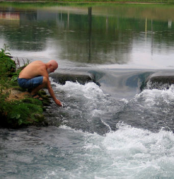 Dean bends over the outflow from the upper spring lake.